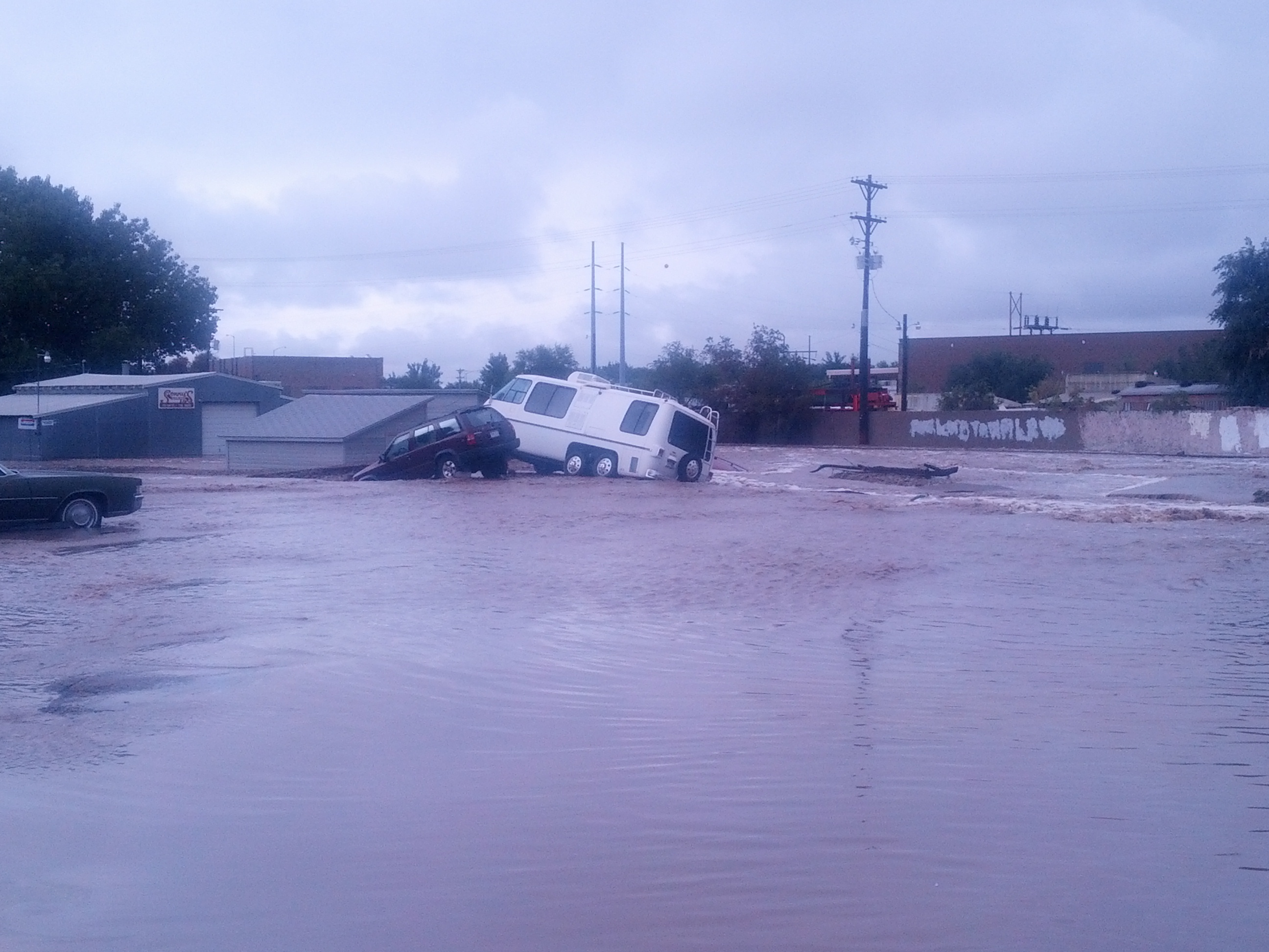 Picture of a car and van in water and on top of something structure.