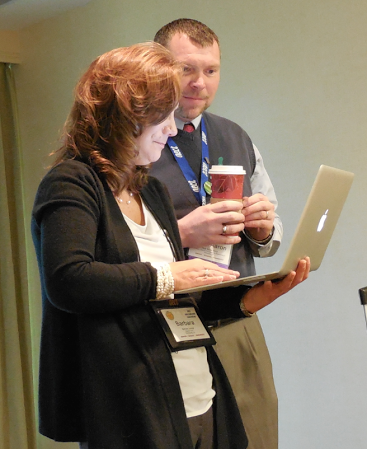 Faculty looking at a laptop drinking coffee