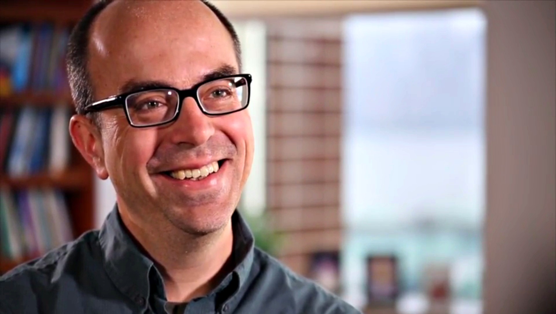 Dr. Ray Klump headshot, image of man with glasses smiling in front of office bookcase