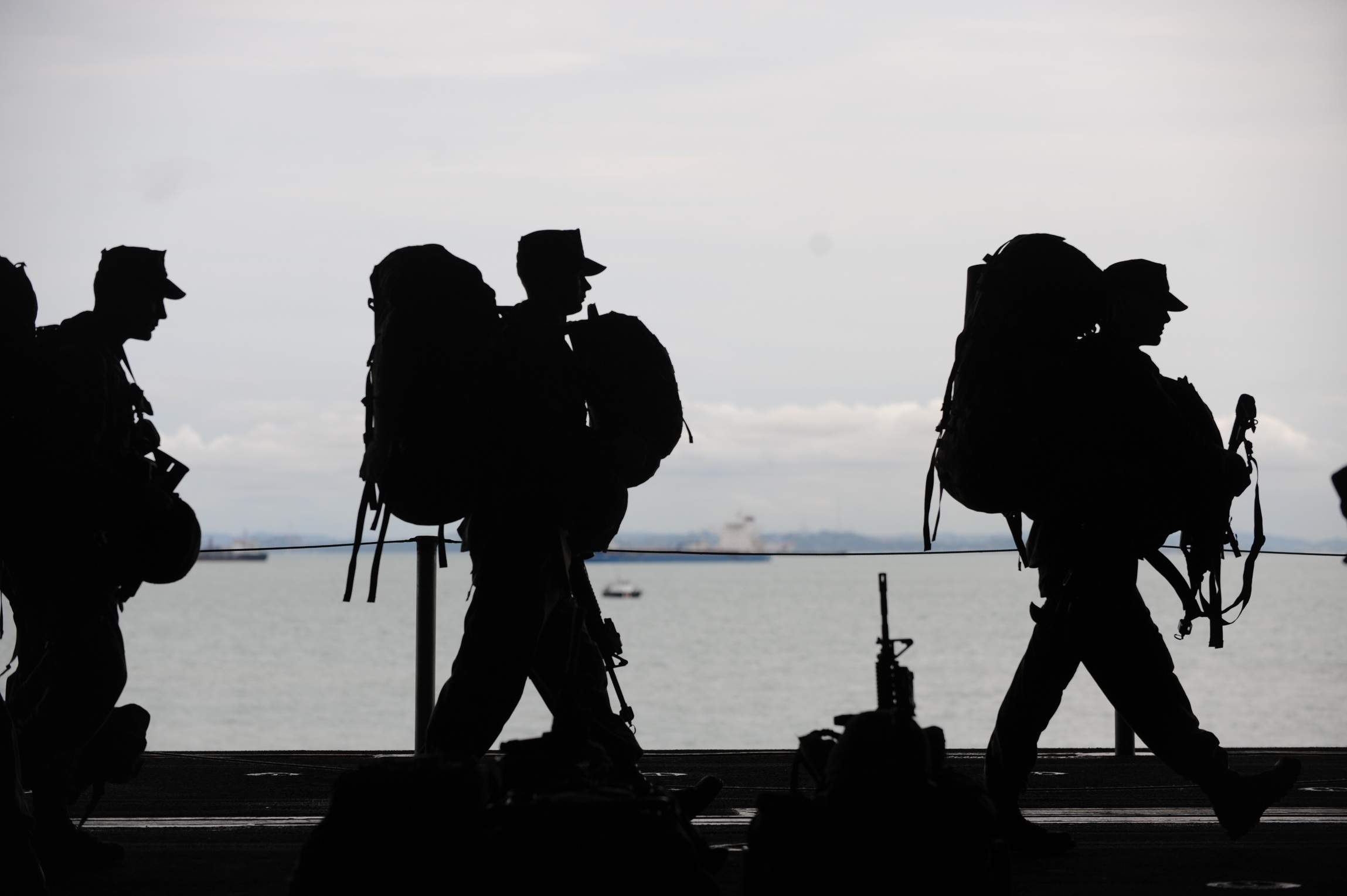 Soldiers carrying packs walking near water