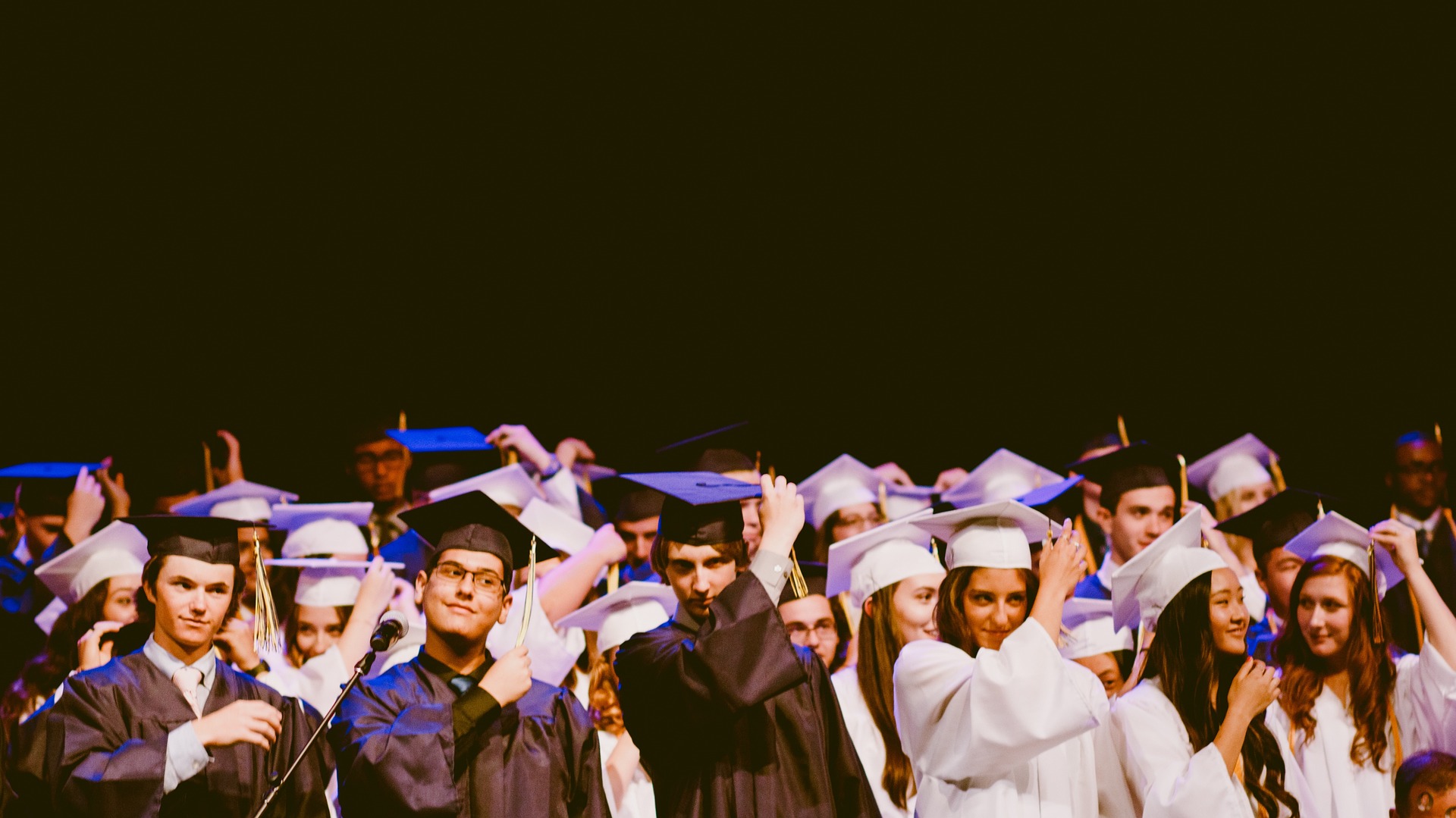 crowd of college graduates moving tassles on caps from one side to the other