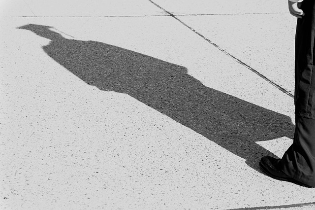 Picture of a college graduate looking into his shadow on the sidewalk.