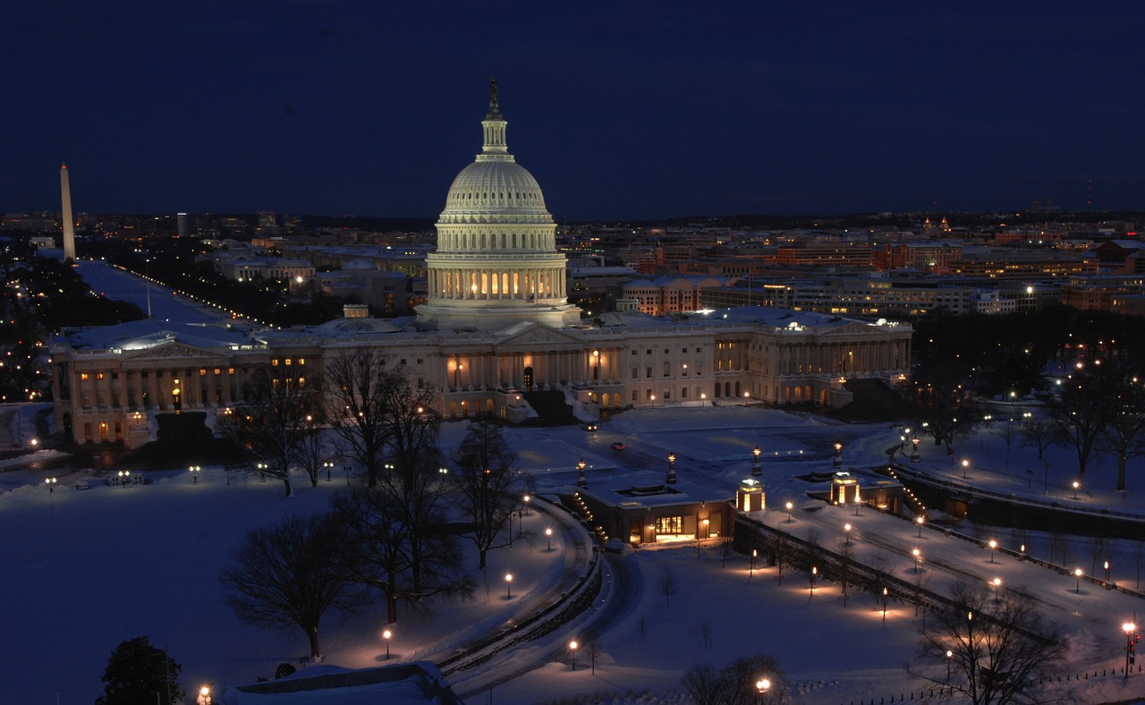 the US capital building in Washington DC at night. The grounds are covered in snow.