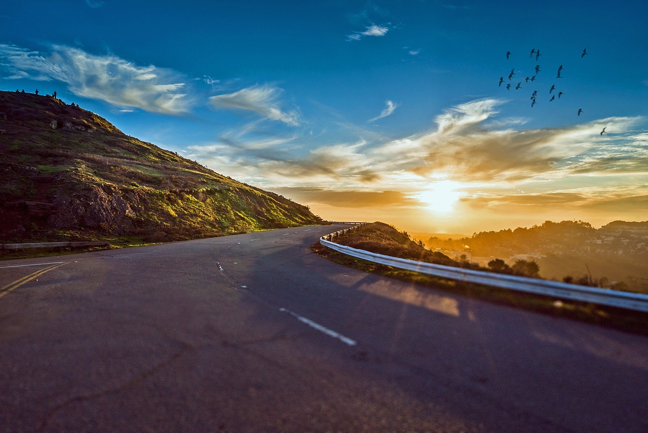 a winding road next to a mountain