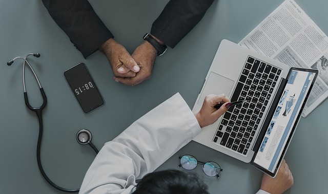 Picture of doctor speaking with a patient, while using a laptop.