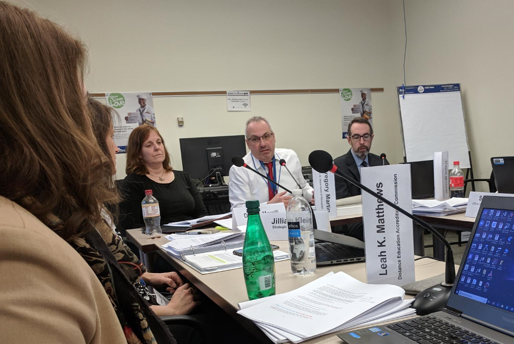 Three women and two men are sitting at a table with microphones in front of them. Three of them have the name cards in front of them on end.