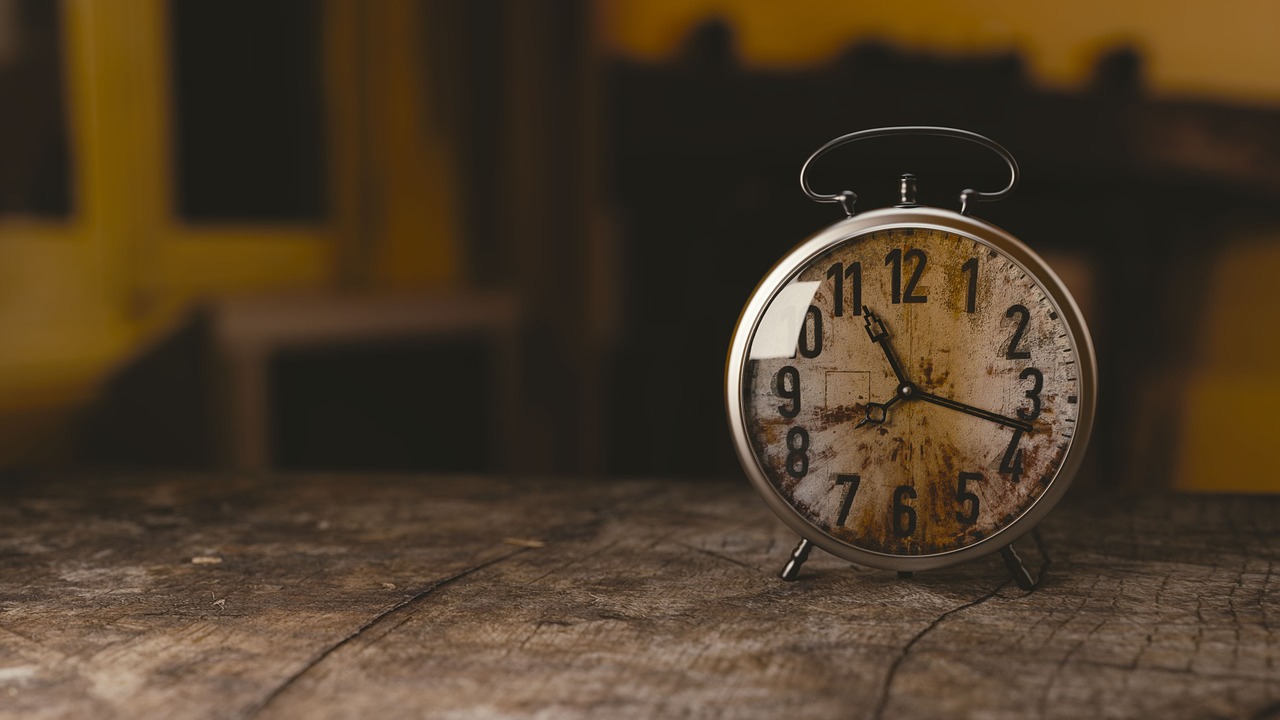 A small analog clock on a table. The time reads 11:15.