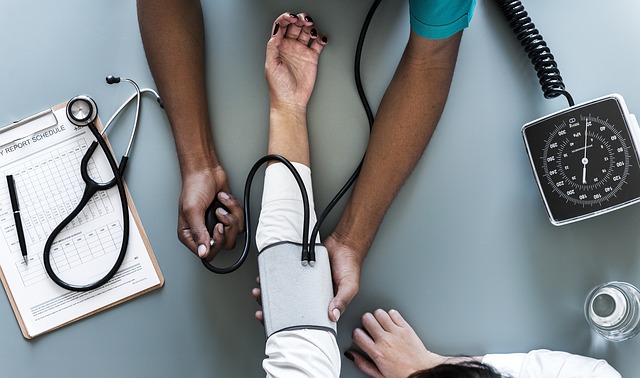 Nurse holding a patient's arm and taking his/her blood pressure.