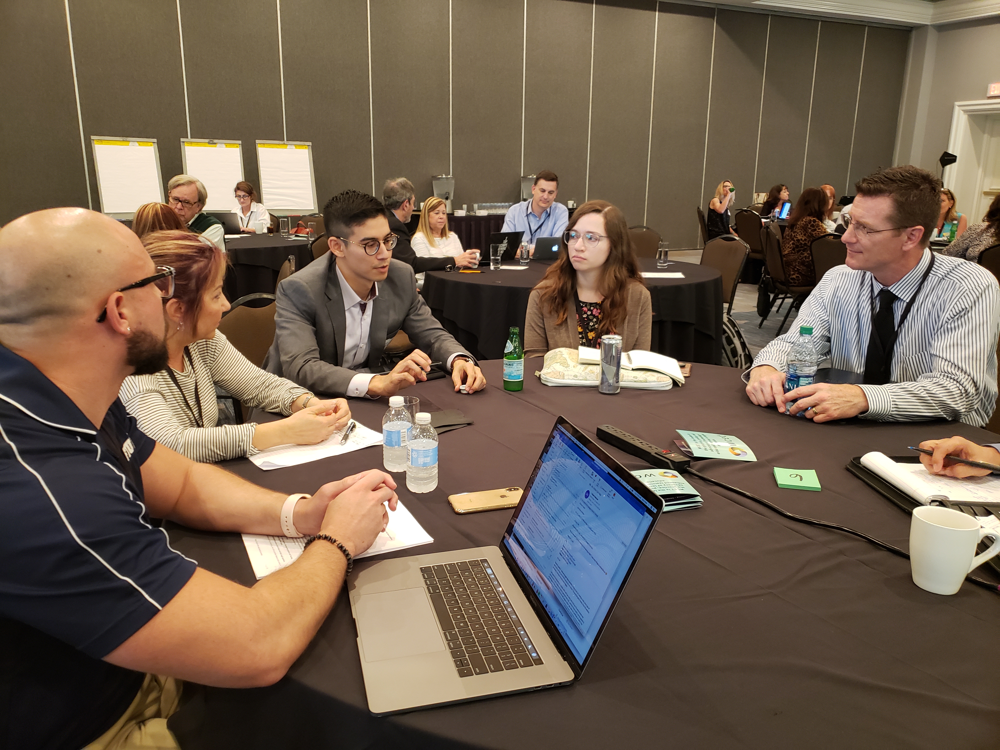 Several attendees sit around a circle table discussing