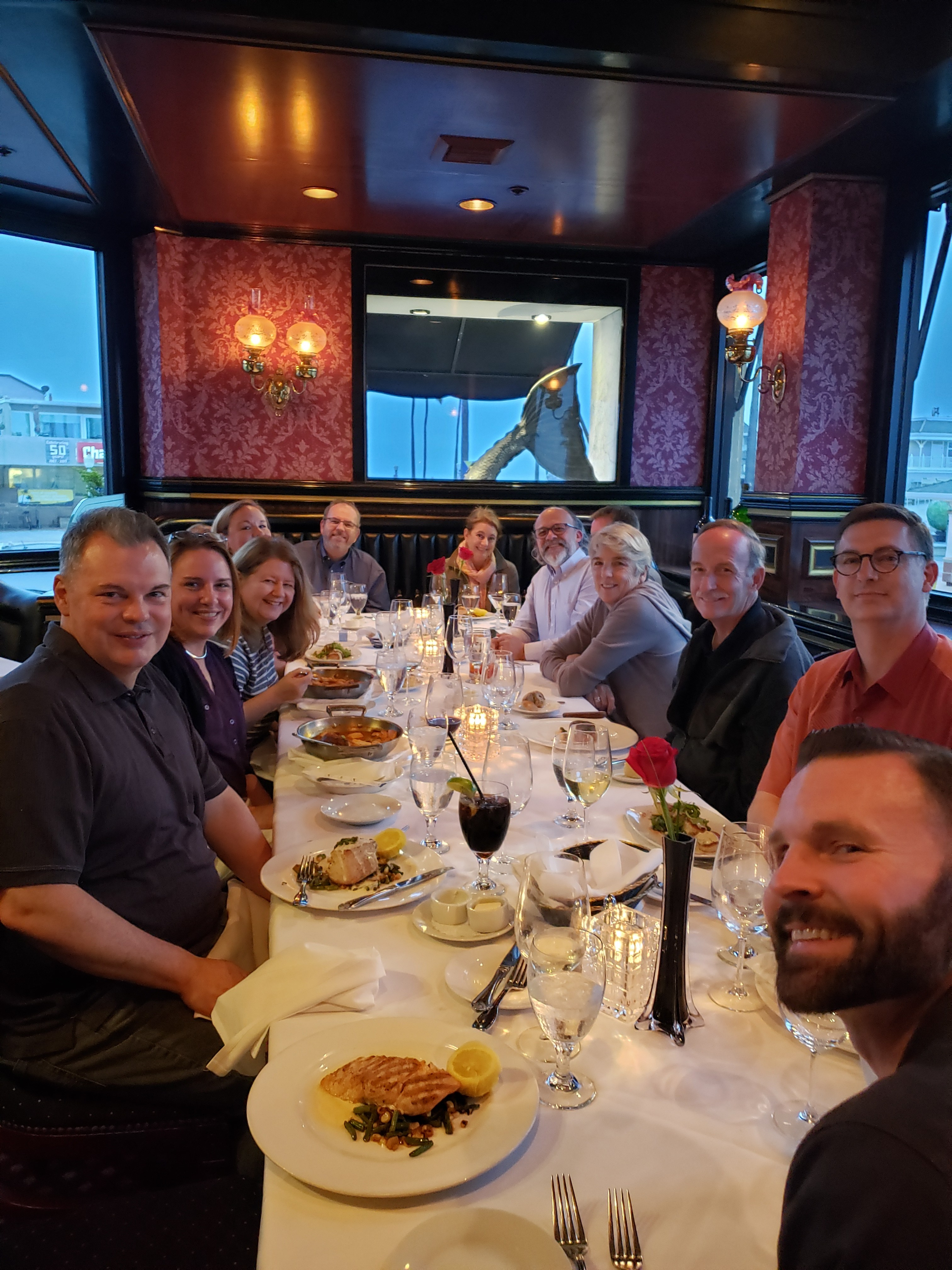 Several event attendees sit at a long dinner table