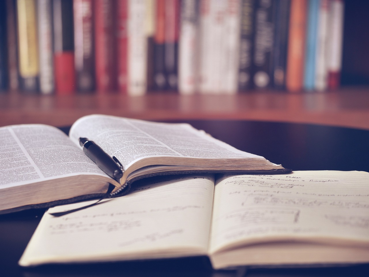 two books on a table with a pen