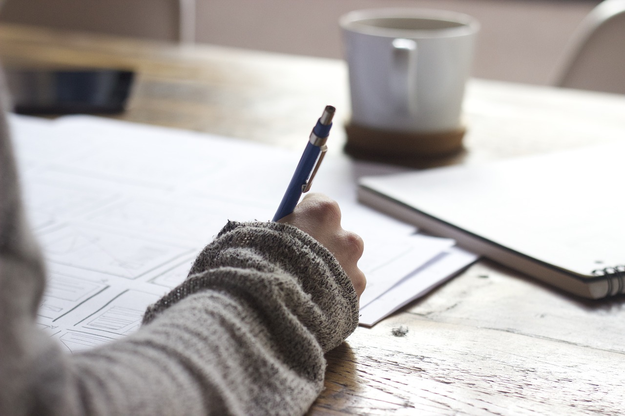 Someone writing on a piece of paper with a pen