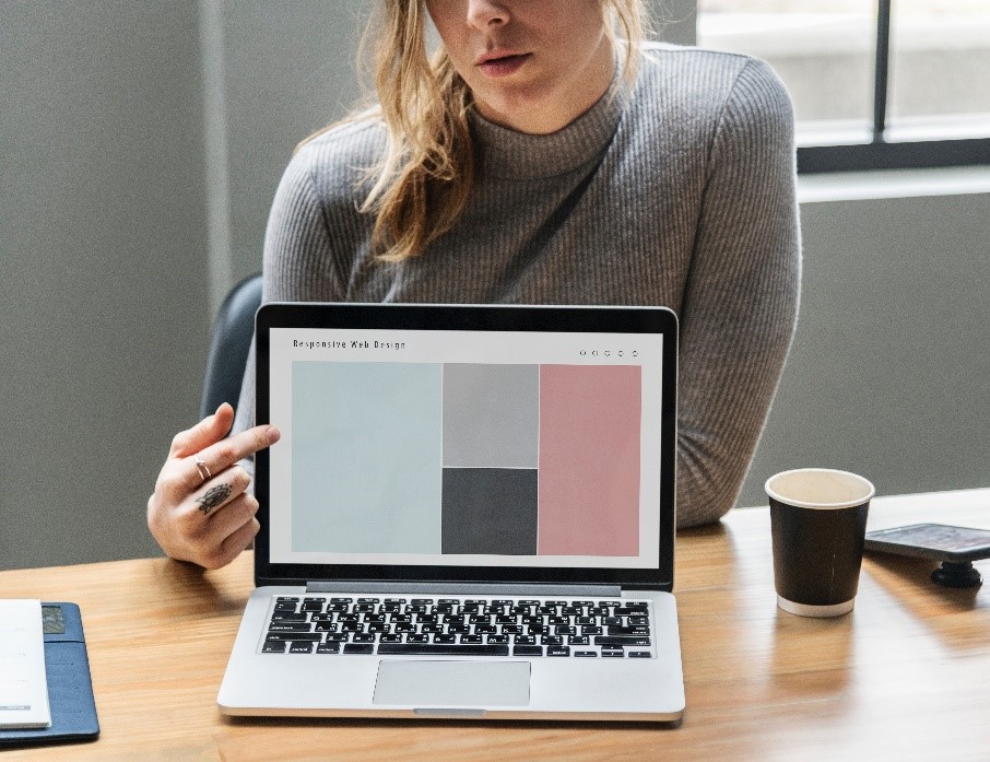 Photo showing a woman pointing at a computer screen, which shows a responsive design website layout.