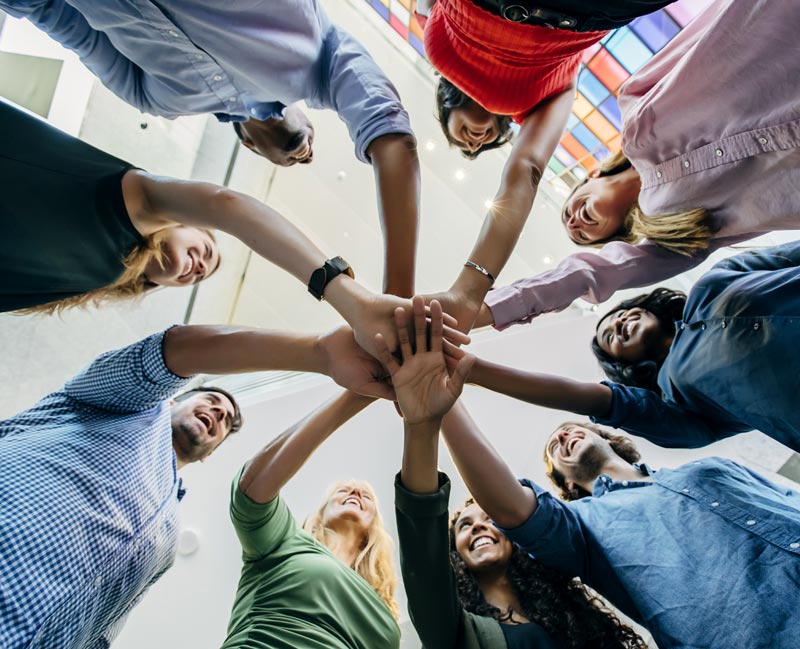 several people in a circle with their hands held together