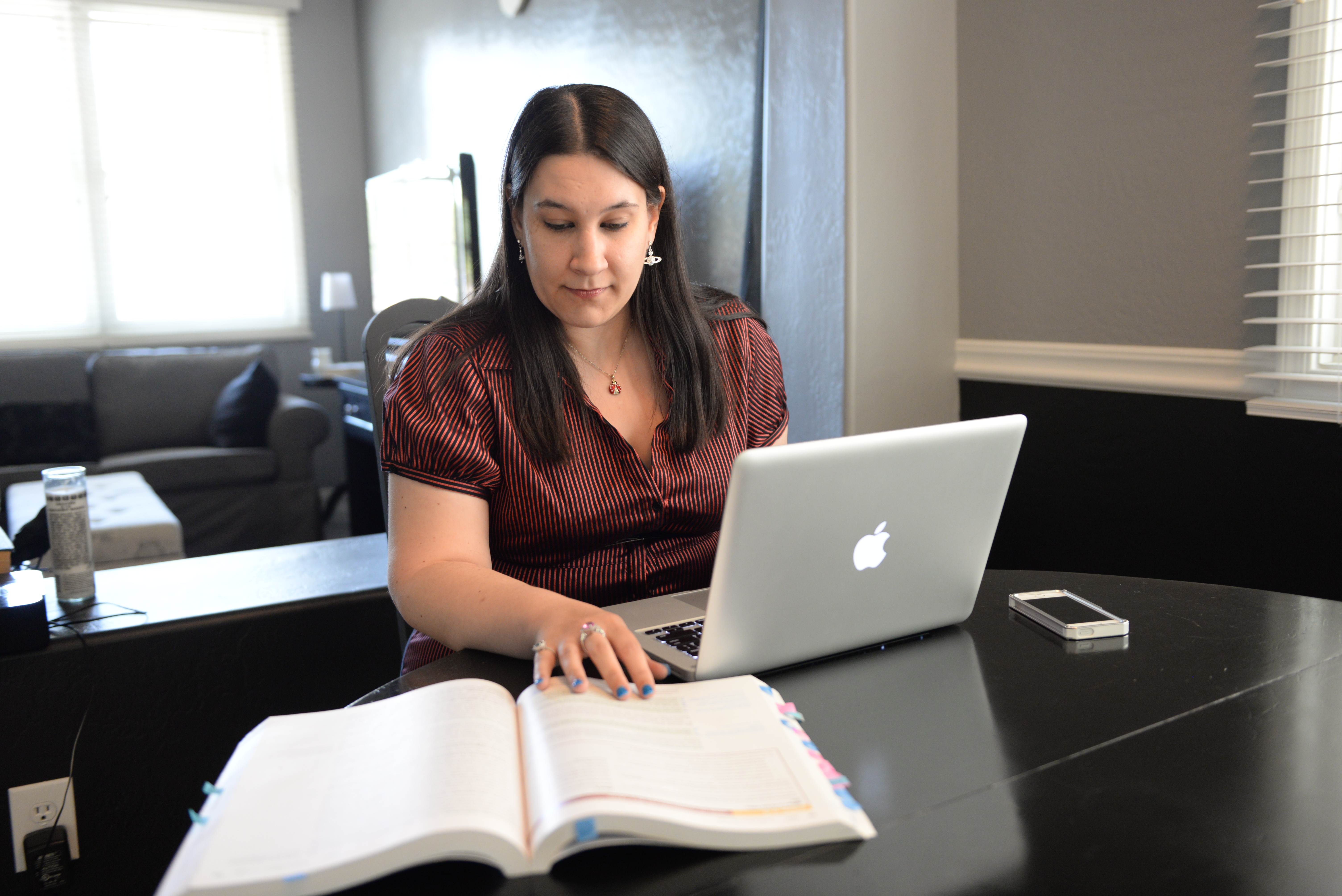 A student at a laptop computer looking at a textbook