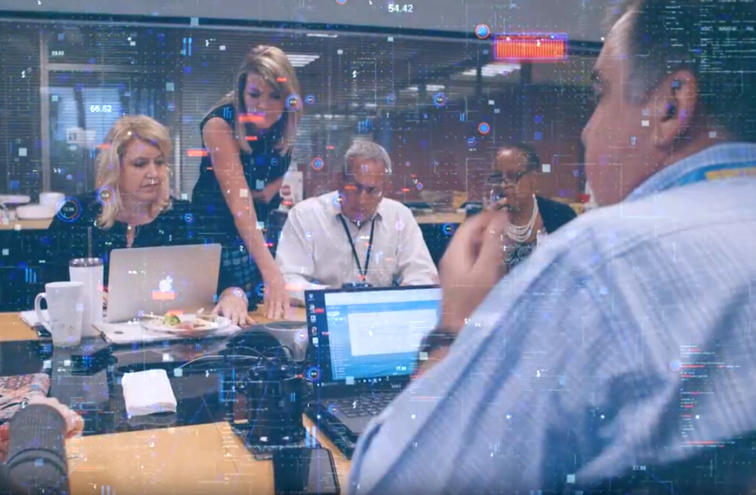 Several faculty members at a table with laptops