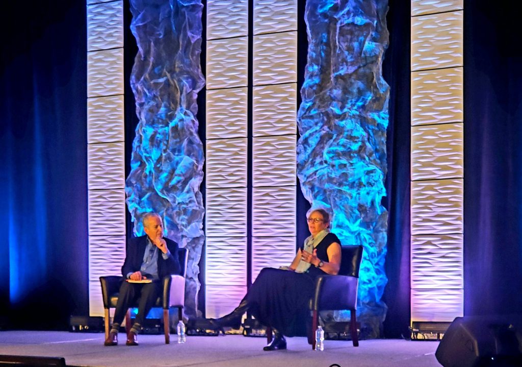 Diane Auer Jones and Michael Goldstien sit on stage during a session