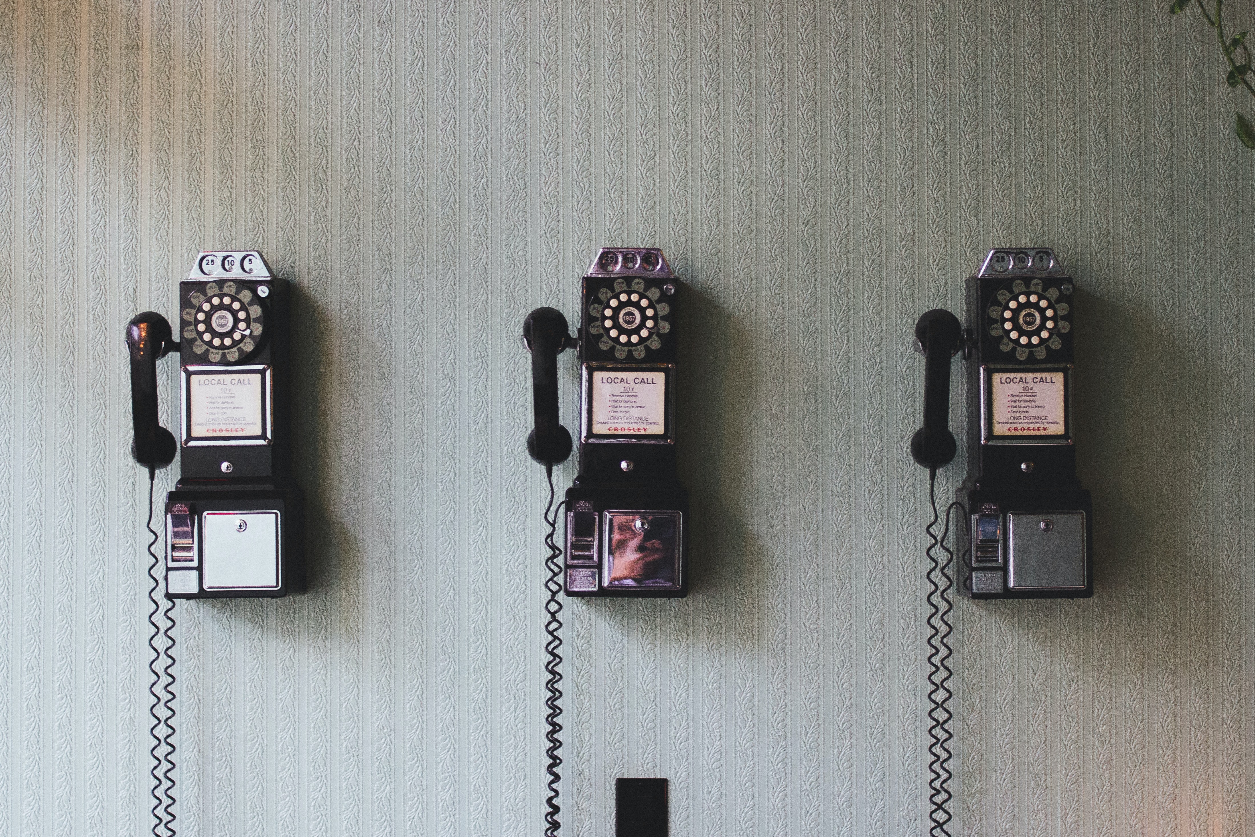 three rotary phones on a wall