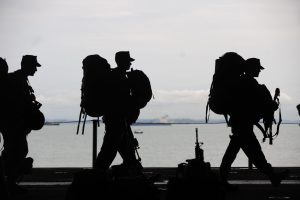 several military members in service uniform in front of a body of water