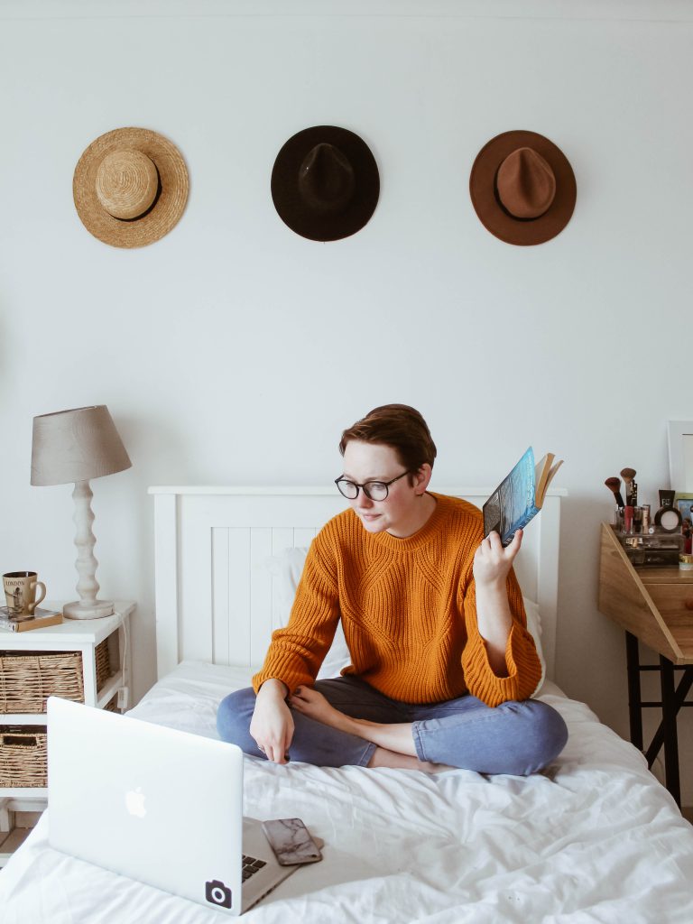 a person studying while sitting on their bed.