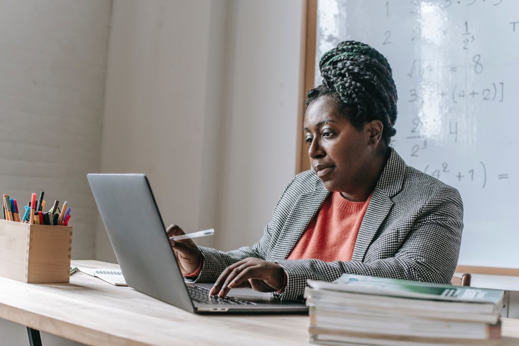 Black woman sitting at a laptop in a classroom.