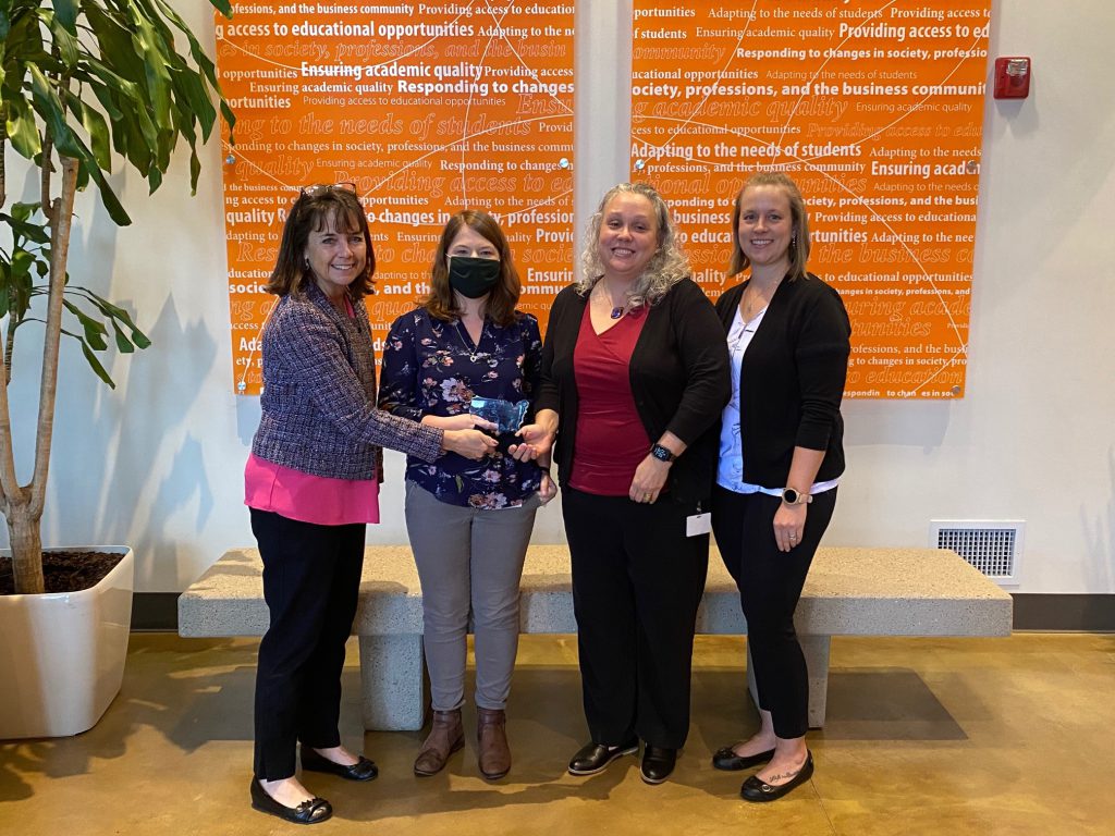 Group of women standing in a lobby with their SAN award.