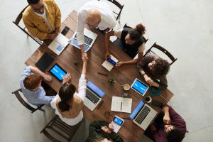 photo of people in a work meeting,  two are shaking hands over the table.