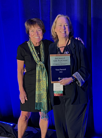 Photo of two womenin front of a blue drape