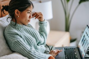 Woman sitting on a couch doing online coursework. 