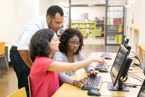 Three students work together on a computer. 