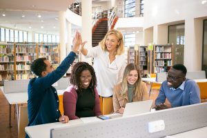 group of students high fiving around a computer. 