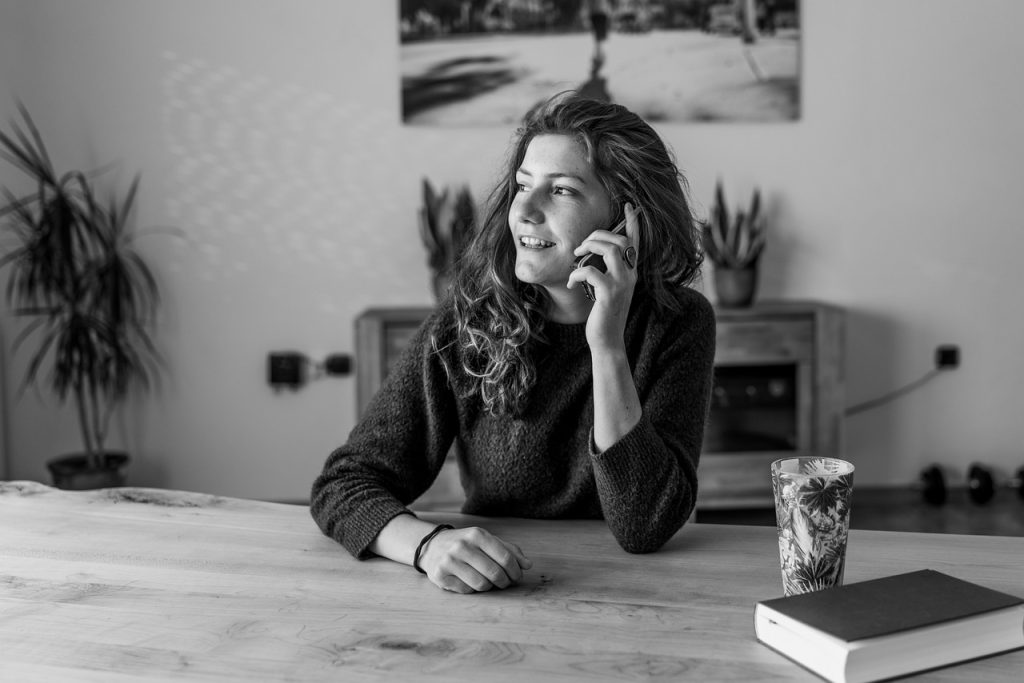 a woman sitting at a table and talking on a cell phone