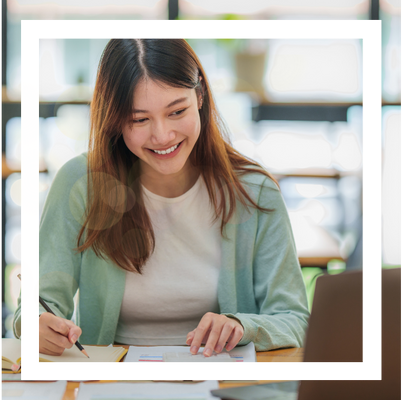 A young woman smiling while working on a laptop