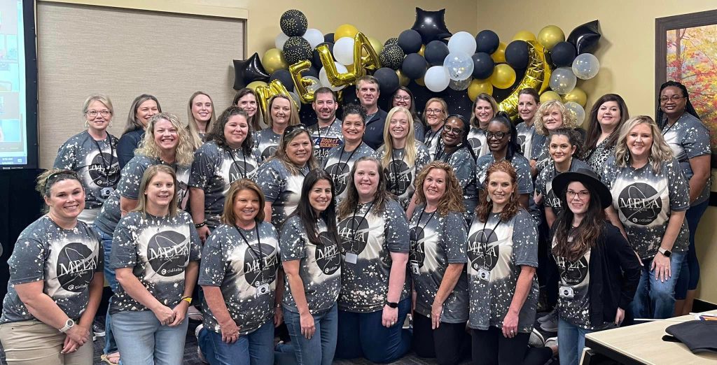 A group of professionals wearing MELA shirts - each representing the 15 Mississippi community colleges and the MCCB at the 2023 Mississippi eLearning Association (MELA) Retreat.